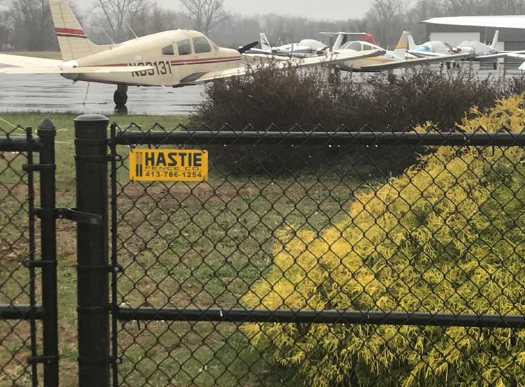 Chain link fence in front of a small prop airplane