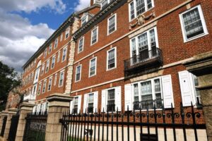 Wrought iron fence in front of a brick building with white-trimmed windows.